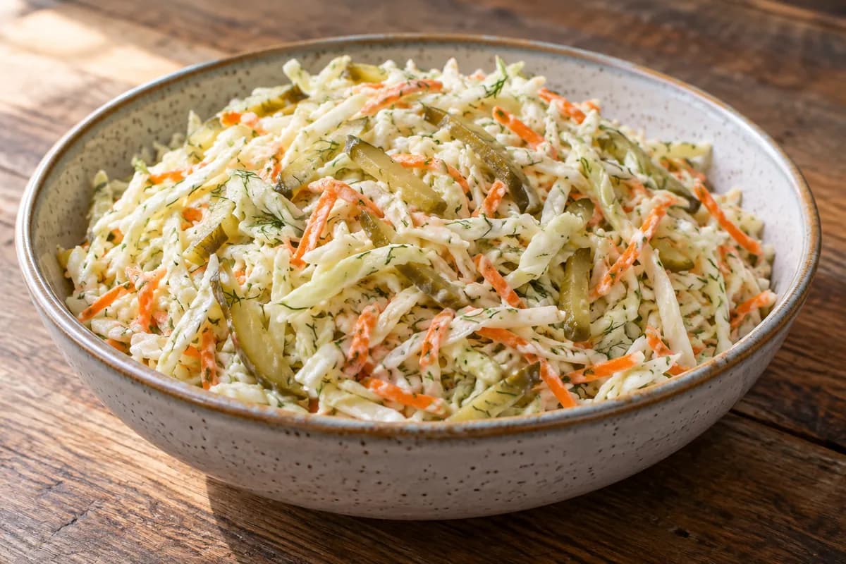 Shredded cabbage and carrot with thin pickle matchsticks.