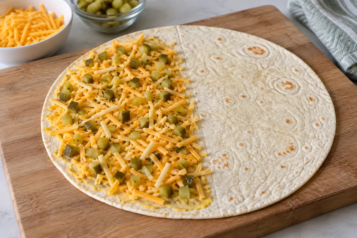 Cheddar and diced pickle layered over one half of a tortilla.
